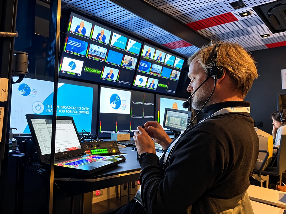 Live streaming since 2004 – OxygenStream technician in the control room wearing an intercom headset in front of a wall of monitoring screens